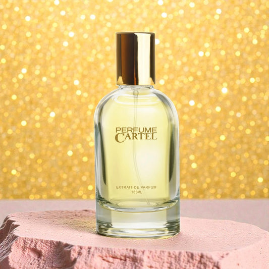 Perfume Cartel bottle on a pink surface with a glittery gold background