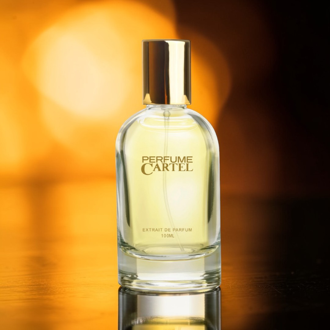 Perfume Cartel bottle on a reflective surface with a warm background